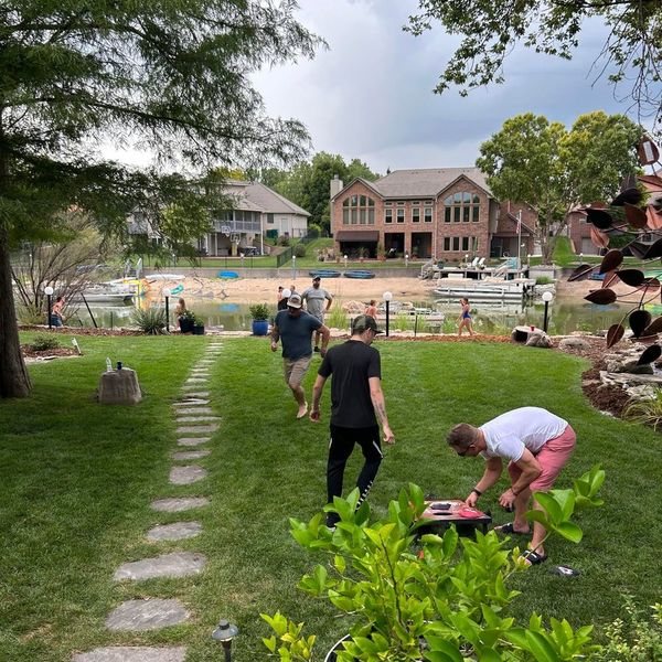 Cornhole game in backyard with lake and houses across the way
