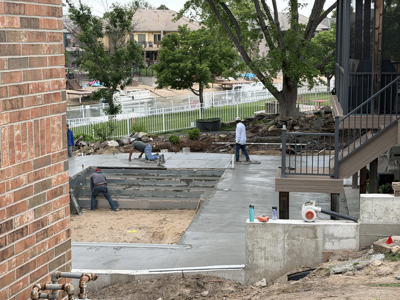 Crew floating fresh concrete on the new pool deck, screened porch and composite stairs to the right