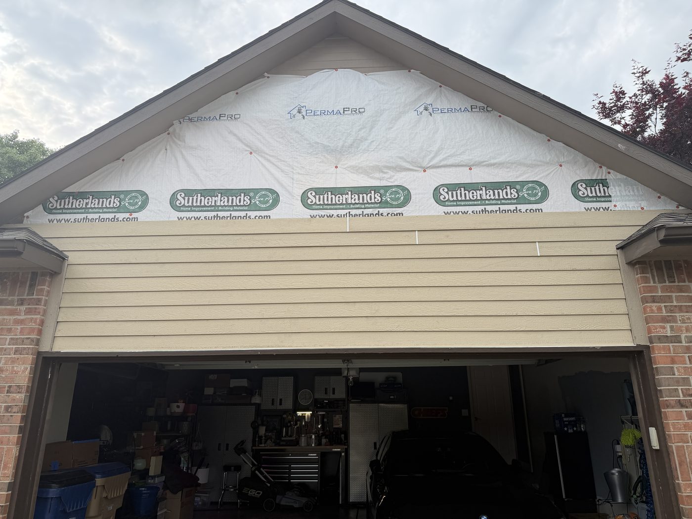 House wrap and fresh lap siding going up on a garage gable, windows in progress